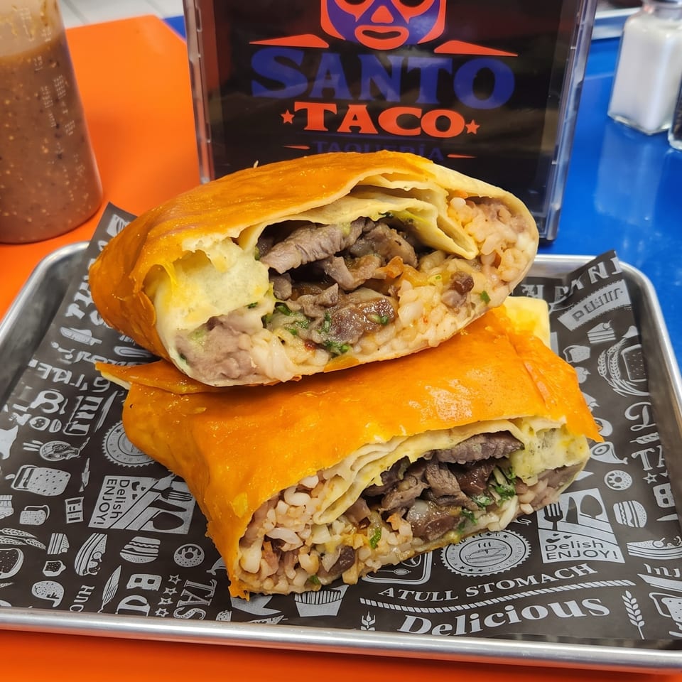 Two large Santo Taco burritos, cut in half, revealing meat and rice filling, on a metal tray.
