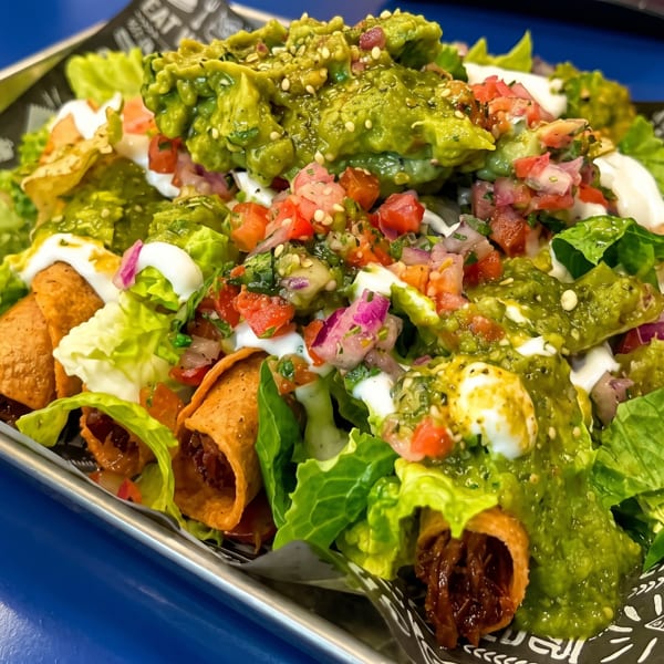 Crispy taquitos topped with guacamole, pico de gallo, sour cream, and fresh lettuce.