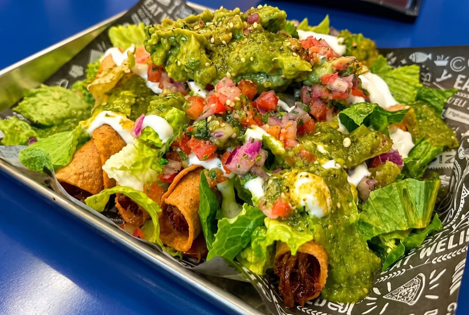 Crispy taquitos topped with guacamole, pico de gallo, sour cream, and fresh lettuce.